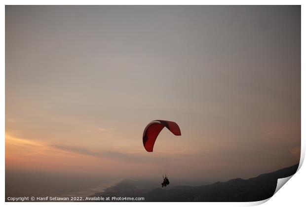 Tandem paragliding over sea and beach at sunset Print by Hanif Setiawan