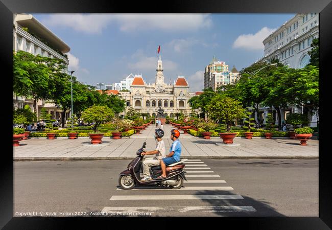 A motorcyclist rides along the road.past a statue of Ho Chi Minh Framed Print by Kevin Hellon