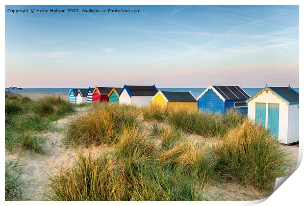 Beach huts in the sand dunes at Southwold  Print by Helen Hotson