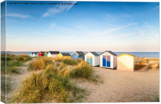 Colourfull beach huts in the sand dunes at Southwold Canvas Print by Helen Hotson