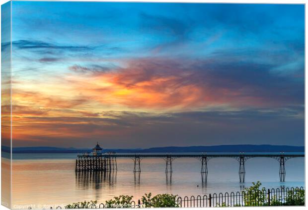Clevedon Pier with the setting sun lighting up the cloud cover Canvas Print by Rory Hailes
