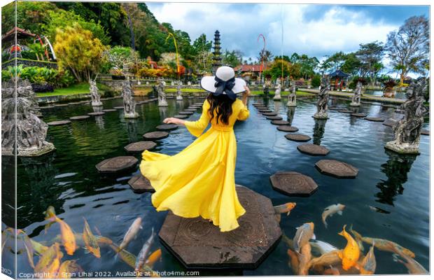 Woman standing in pond with colorful fish at Tirta Gangga Water  Canvas Print by Stan Lihai