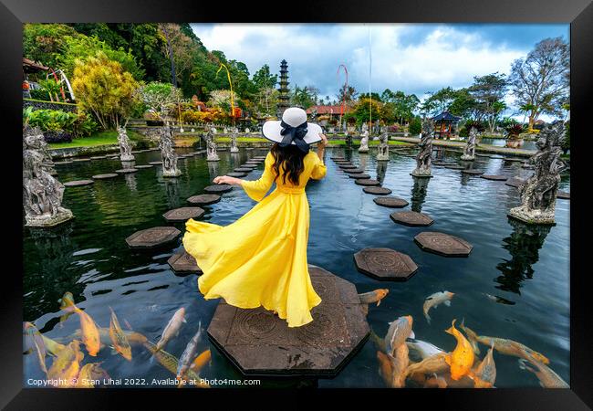 Woman standing in pond with colorful fish at Tirta Gangga Water  Framed Print by Stan Lihai