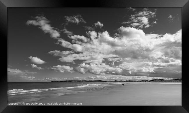 A lone beach walker under a dramatic sky Framed Print by Joe Dailly