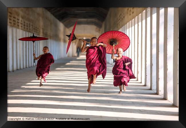 Novice monks with umbrellas running at temple, Bagan, Myanmar Framed Print by Matteo Colombo