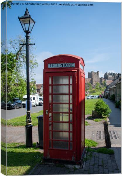 Bamburgh Castle, village and red telephone box Canvas Print by Christopher Keeley