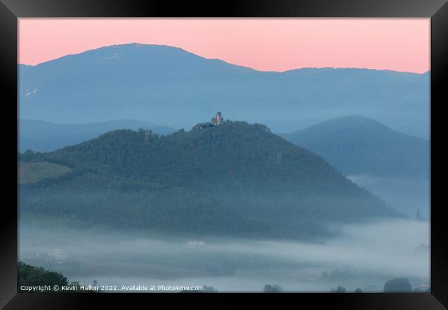 Hilltop castle surrounded by early morning mist Framed Print by Kevin Hellon