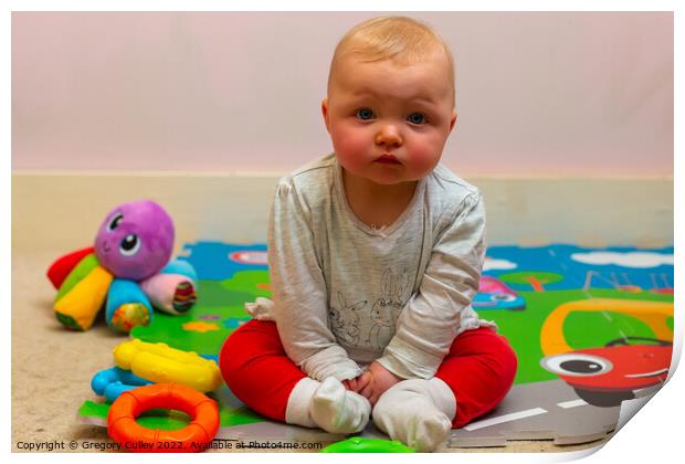 A baby girl sitting on a colourful mat with her toys Print by Gregory Culley