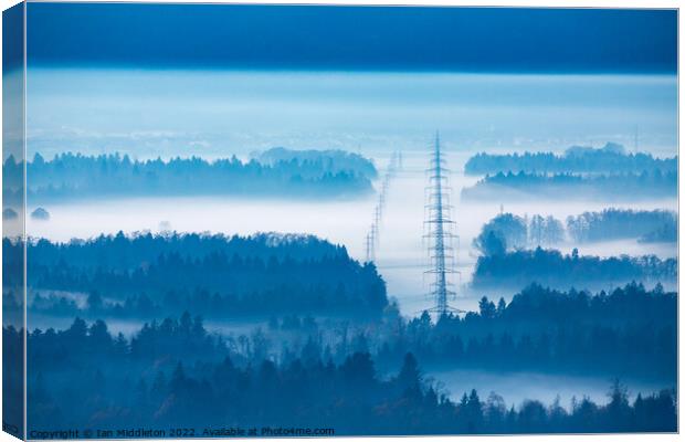 Electricity pylons in the mist. Canvas Print by Ian Middleton