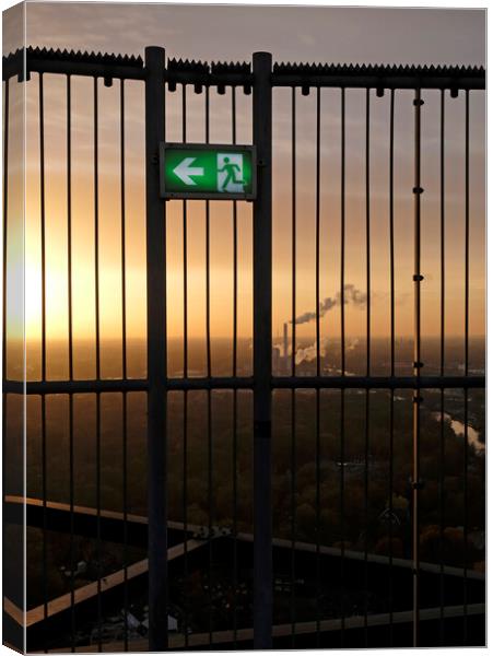 An emergency exit sign with an industrial site in the background Canvas Print by Lensw0rld 