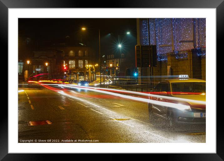 During the Evening of a Rainy Night, a Yellow Taxi Travels Along a Wet Road. Framed Mounted Print by Steve Gill