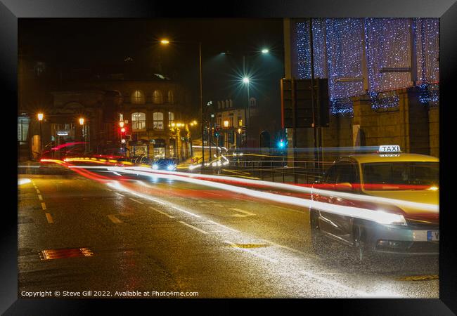 During the Evening of a Rainy Night, a Yellow Taxi Travels Along a Wet Road. Framed Print by Steve Gill