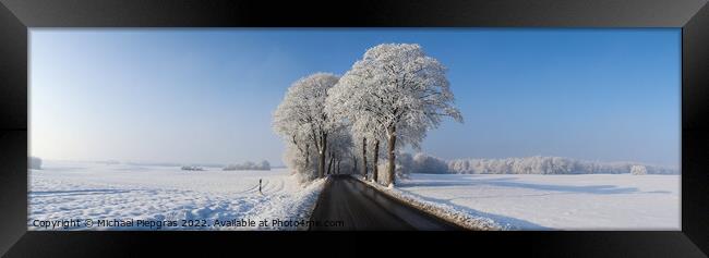 View of a snow-covered country road in winter with sunshine and  Framed Print by Michael Piepgras