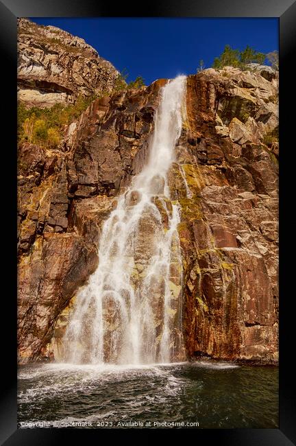 View of Norwegian waterfall cascading into Lysefjorden fjord  Framed Print by Spotmatik 