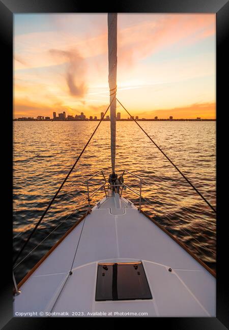 Bow of yacht sailing towards cityscape at sunrise Framed Print by Spotmatik 