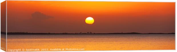 Panoramic orange sky over tranquil ocean at sunset Canvas Print by Spotmatik 
