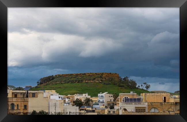 Storm over the hill with buildings, Gozo Island. Framed Print by Maggie Bajada