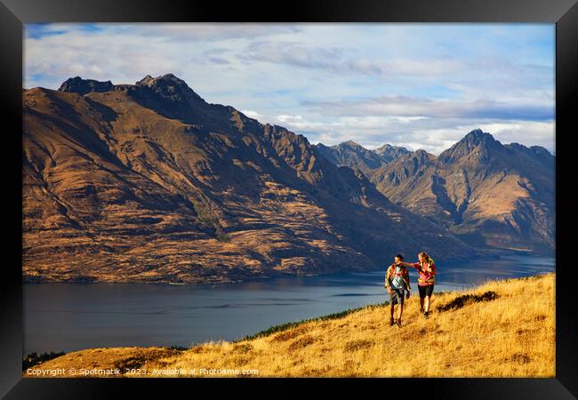 Hikers on trekking expedition enjoying view Lake Wakatipu  Framed Print by Spotmatik 