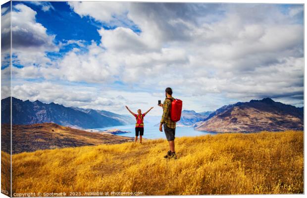Backpacking young couple taking smartphone picture Lake Wakatipu  Canvas Print by Spotmatik 