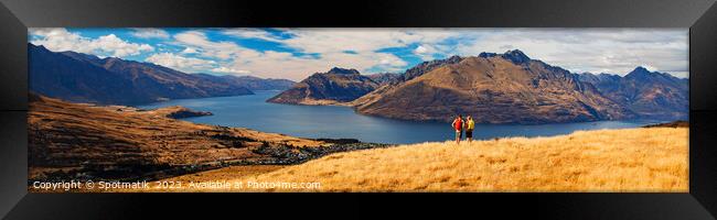 Panorama of New Zealand trekking couple viewing Lake Wakatipu Framed Print by Spotmatik 