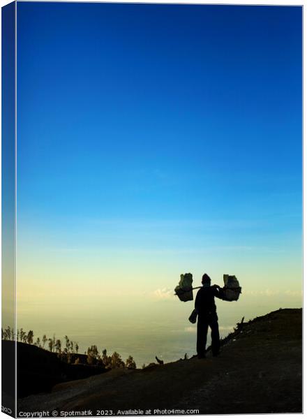 Indonesian worker carrying sulphur blocks from volcano Rim  Canvas Print by Spotmatik 