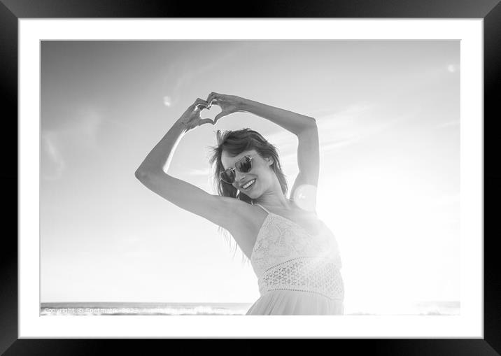 Bohemian girl showing heart sign dancing on beach Framed Mounted Print by Spotmatik 