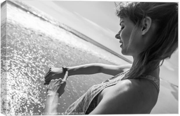 Caucasian female on ocean edge checking sports watch Canvas Print by Spotmatik 