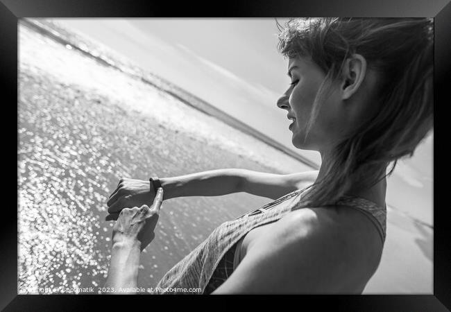 Caucasian female on ocean edge checking sports watch Framed Print by Spotmatik 
