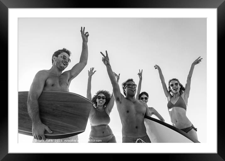 Friends enjoying carefree fun going bodyboarding on beach Framed Mounted Print by Spotmatik 