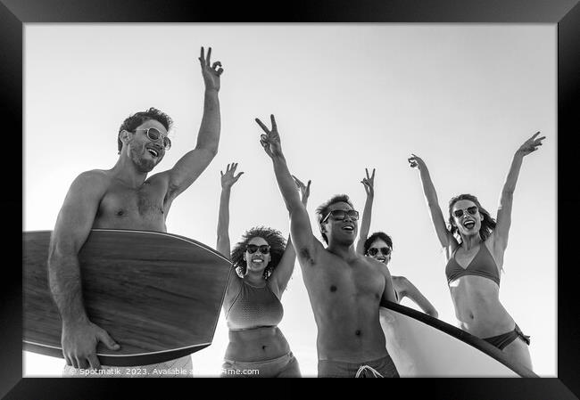 Friends enjoying carefree fun going bodyboarding on beach Framed Print by Spotmatik 