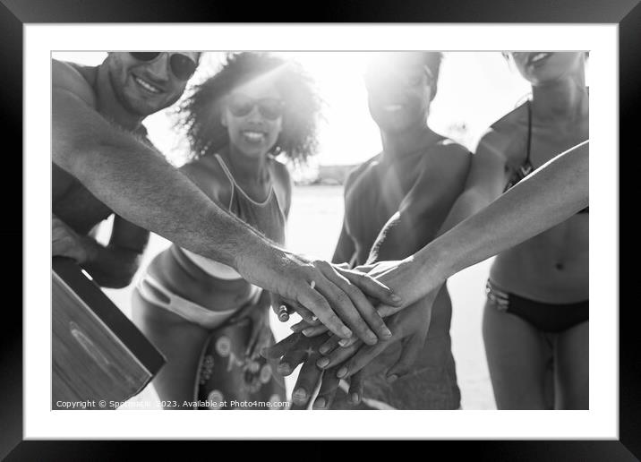 Friends in swimwear joining hands on beach vacation Framed Mounted Print by Spotmatik 