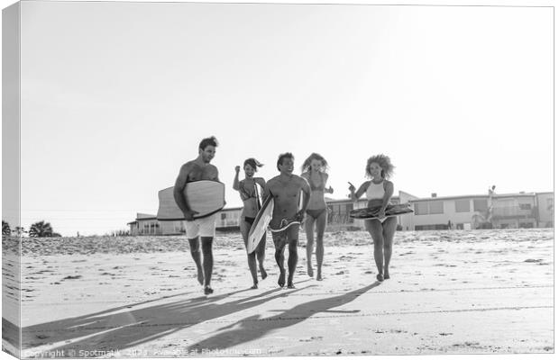 Friends in swimwear running carrying bodyboards on beach Canvas Print by Spotmatik 