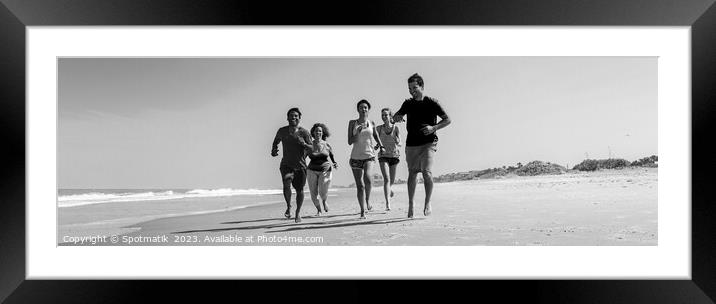 Panoramic view of friends jogging together on beach Framed Mounted Print by Spotmatik 