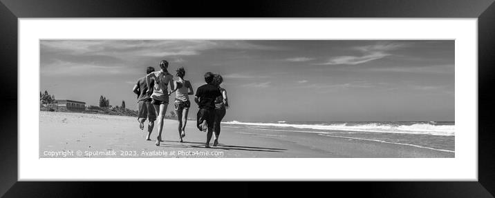 Panoramic view of friends jogging together on beach Framed Mounted Print by Spotmatik 