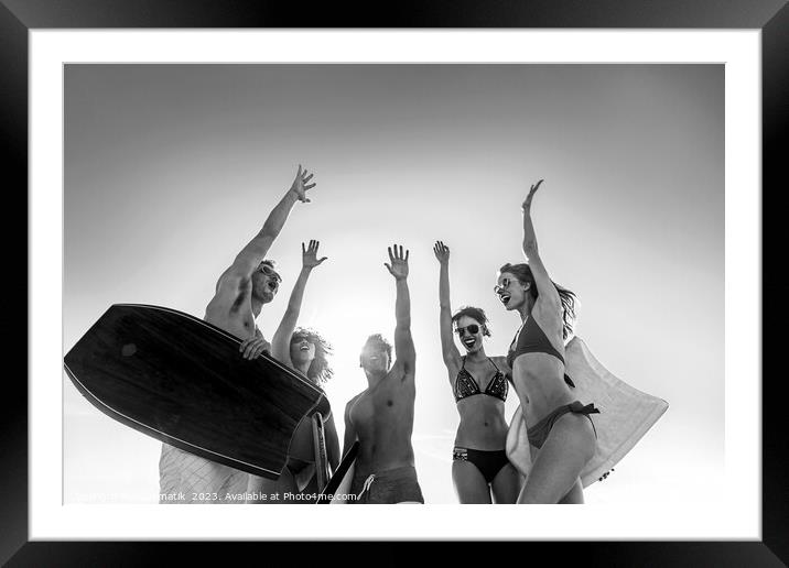 Friends in swimwear carrying bodyboards celebrating fun activity Framed Mounted Print by Spotmatik 