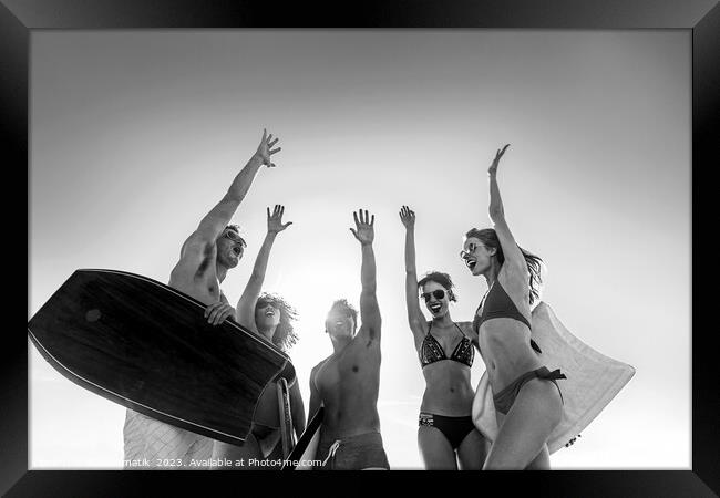 Friends in swimwear carrying bodyboards celebrating fun activity Framed Print by Spotmatik 