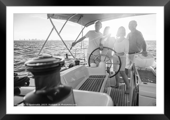 Senior friends enjoying retirement steering yacht at sunset Framed Mounted Print by Spotmatik 