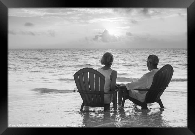 Retired couple enjoying sunset view over ocean Bahamas Framed Print by Spotmatik 