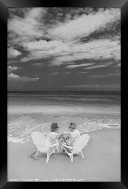 Mature couple on white chairs by ocean Bahamas Framed Print by Spotmatik 