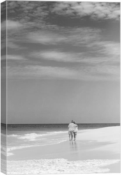 Retired couple walking by ocean in loving embrace Canvas Print by Spotmatik 
