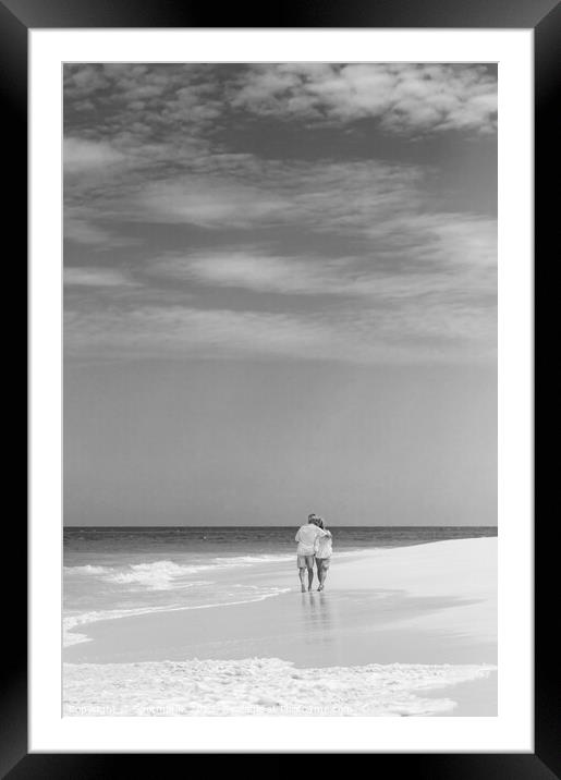 Retired couple walking by ocean in loving embrace Framed Mounted Print by Spotmatik 