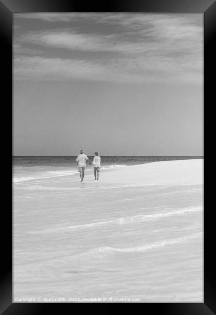 Mature couple walking on beach by ocean Bahamas Framed Print by Spotmatik 