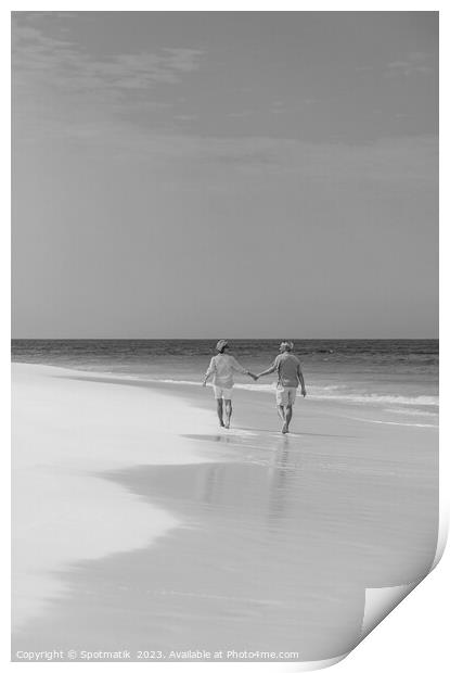 Retired couple holding hands enjoying walk on beach Print by Spotmatik 