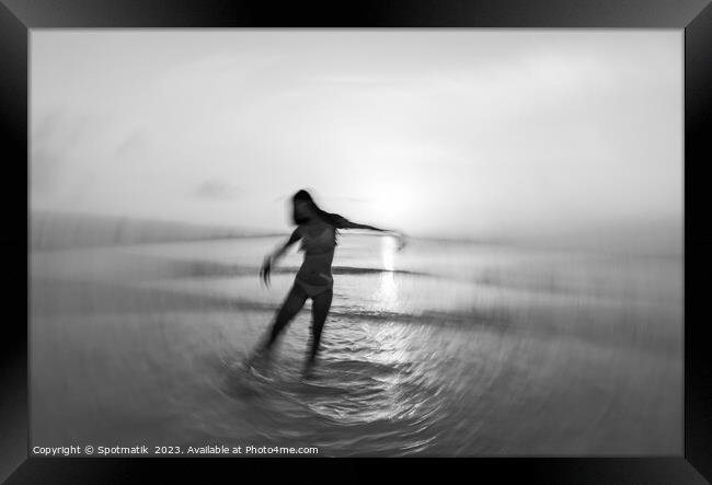 Motion blurred Asian girl dancing in ocean sunset Framed Print by Spotmatik 