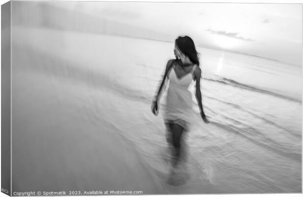 Motion blurred woman walking through waves at sunset Canvas Print by Spotmatik 