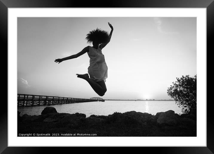 African American woman jumping by ocean at sunset Framed Mounted Print by Spotmatik 