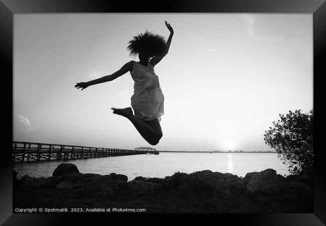 African American woman jumping by ocean at sunset Framed Print by Spotmatik 