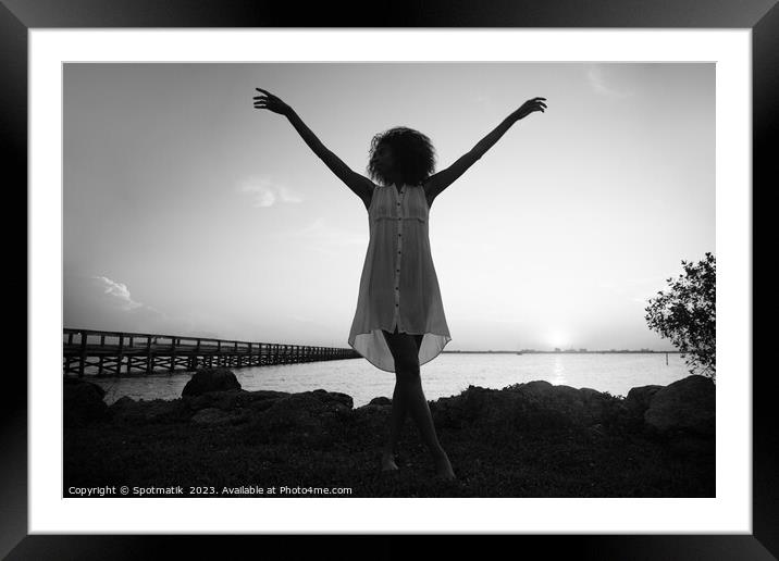 Afro woman dancing at sunset by ocean pier Framed Mounted Print by Spotmatik 