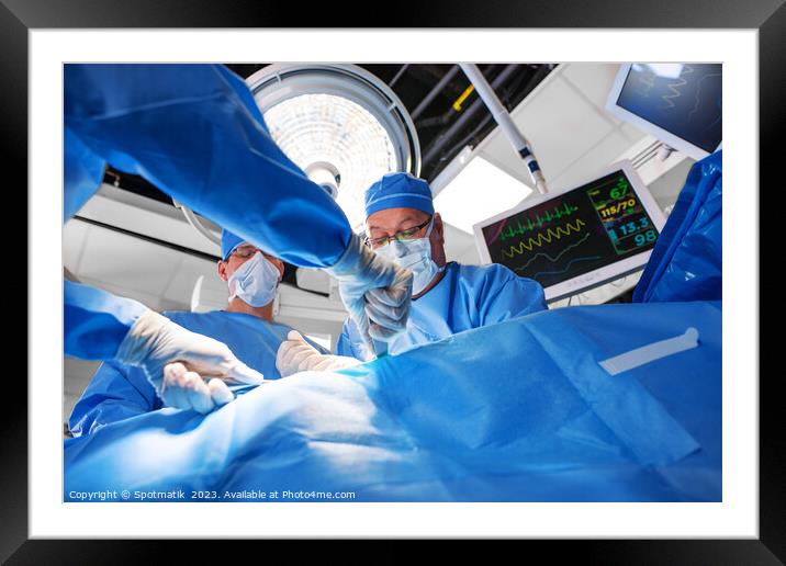Caucasian surgical team wearing scrub operating on patient Framed Mounted Print by Spotmatik 