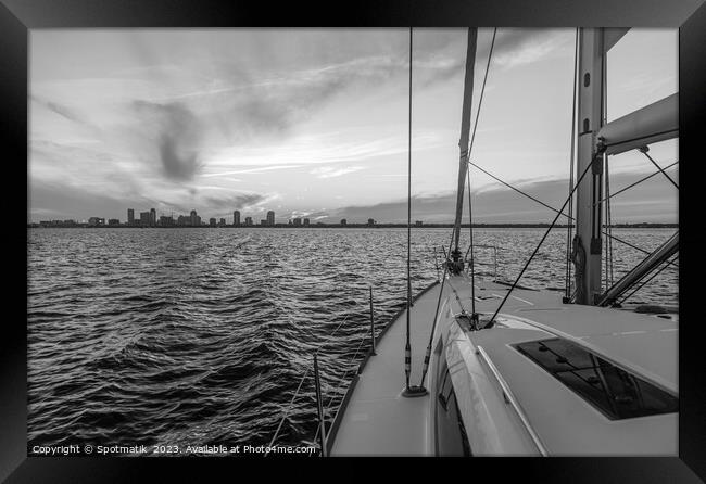 Yacht sailing towards cityscape on horizon at sunset Framed Print by Spotmatik 